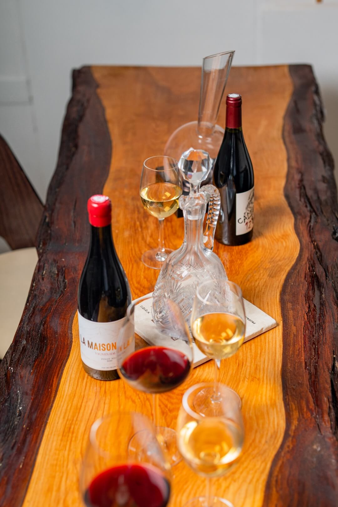 Grande table dans la salle de dégustation privée avec du vin en train de décanté et des bouteilles.