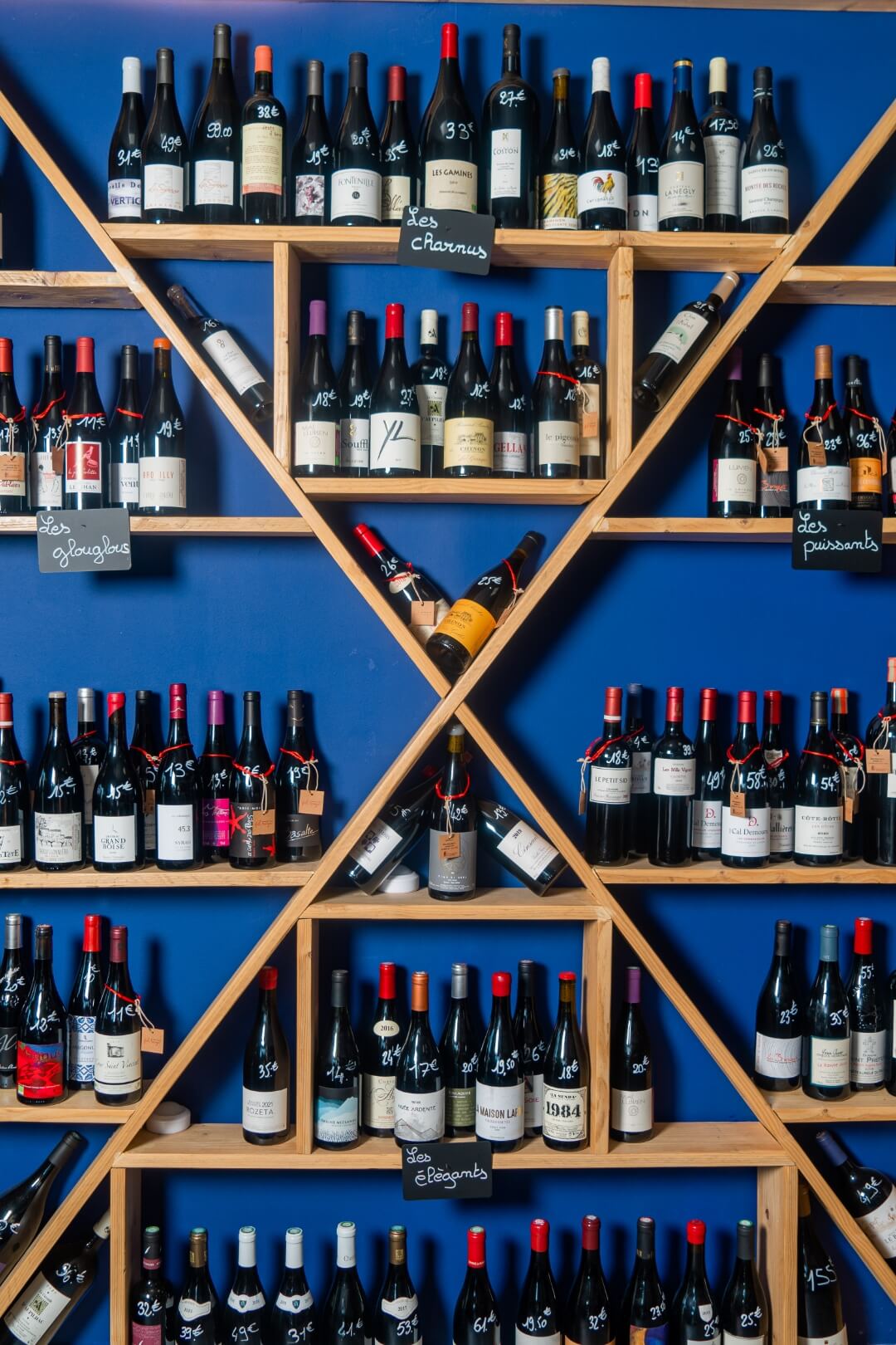 Mur rempli de bouteilles de vins classés par catégorie : charnus, puissants, élegants, glouglous...